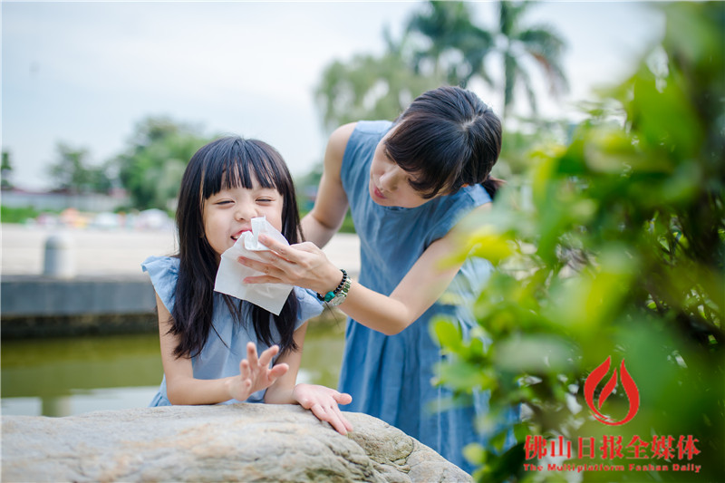 佛山新城一处水池边,一位家长正在为疯玩后准备去吃饭的小朋友擦汗.
